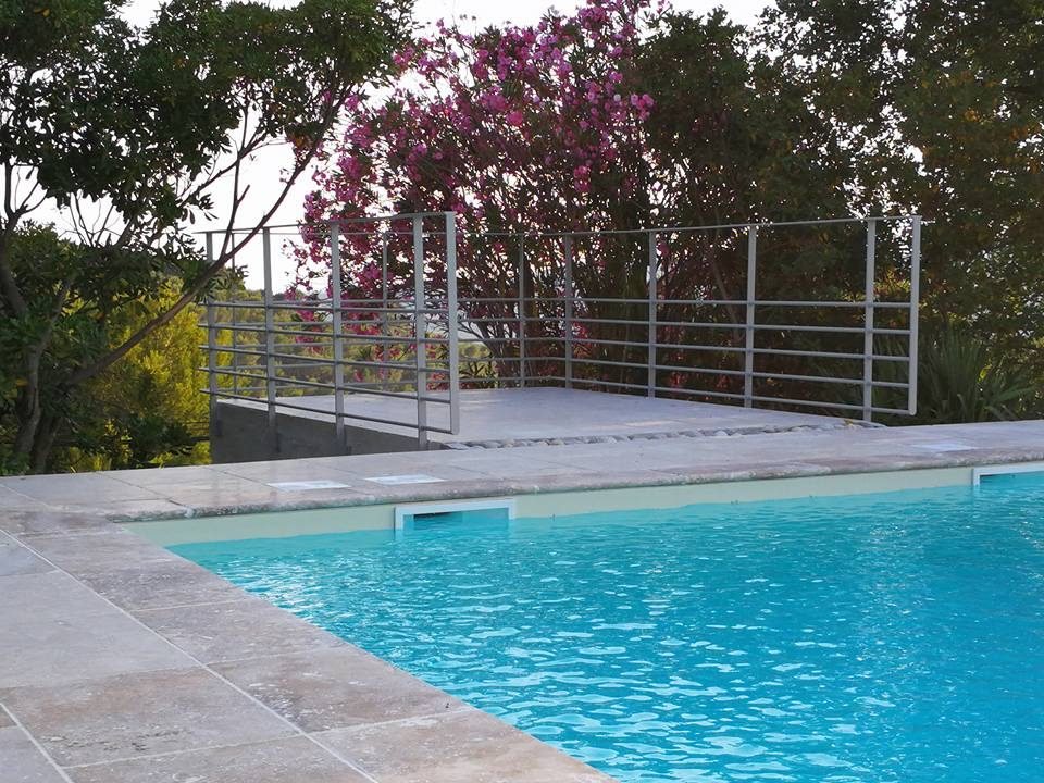 Garde-corps inox à lisses le long d'une piscine, sous un bougainvillier
