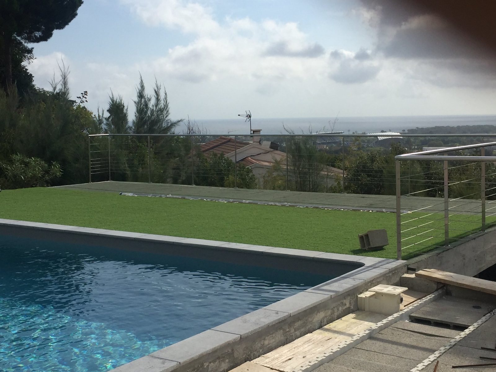 Garde-corps à remplissage verre bordant une piscine à débordement, vue dégagée sur la campagne provençale
