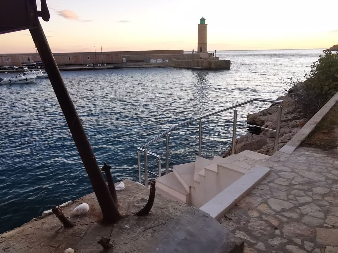 Garde-corps inox sur l'escalier d'un quai, face au phare — Cassis, réalisation Fer'Play