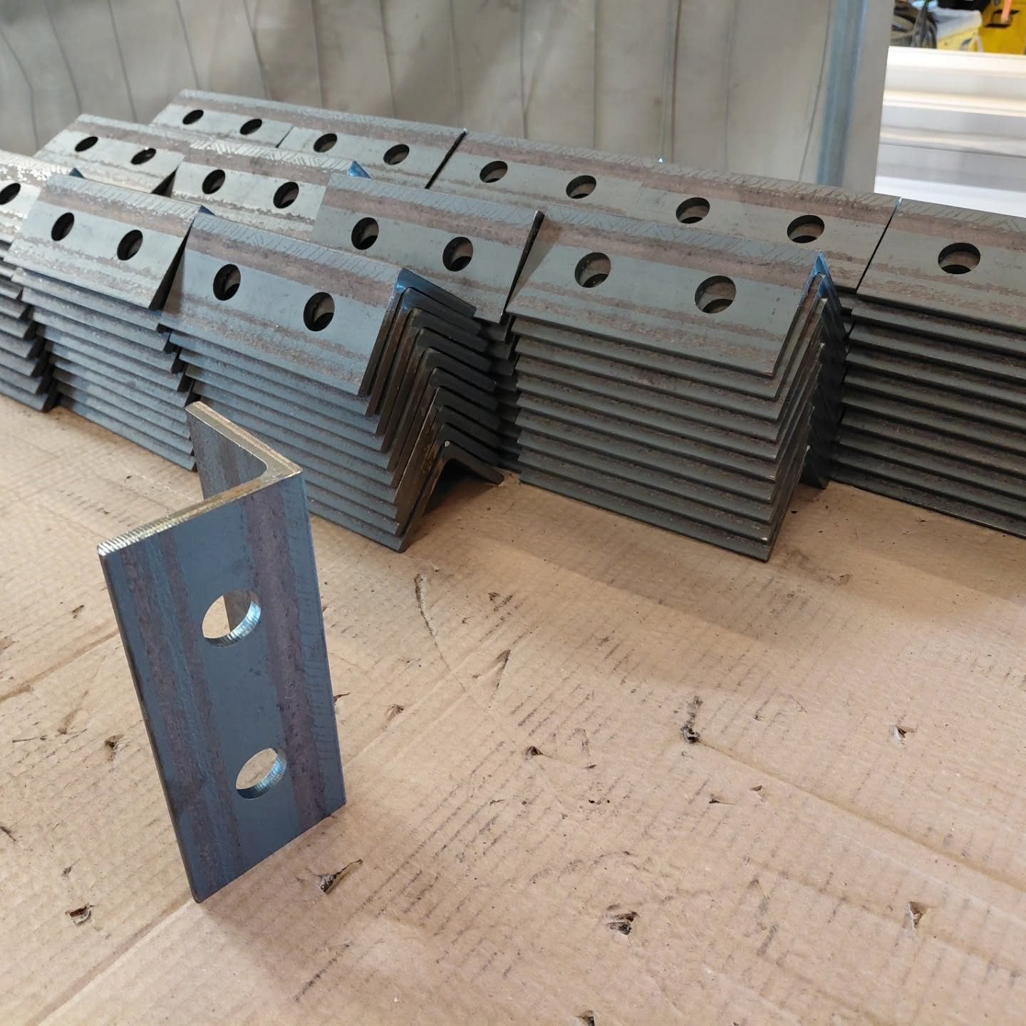 Série de platines et d'équerres acier percées au laser, en attente d'assemblage