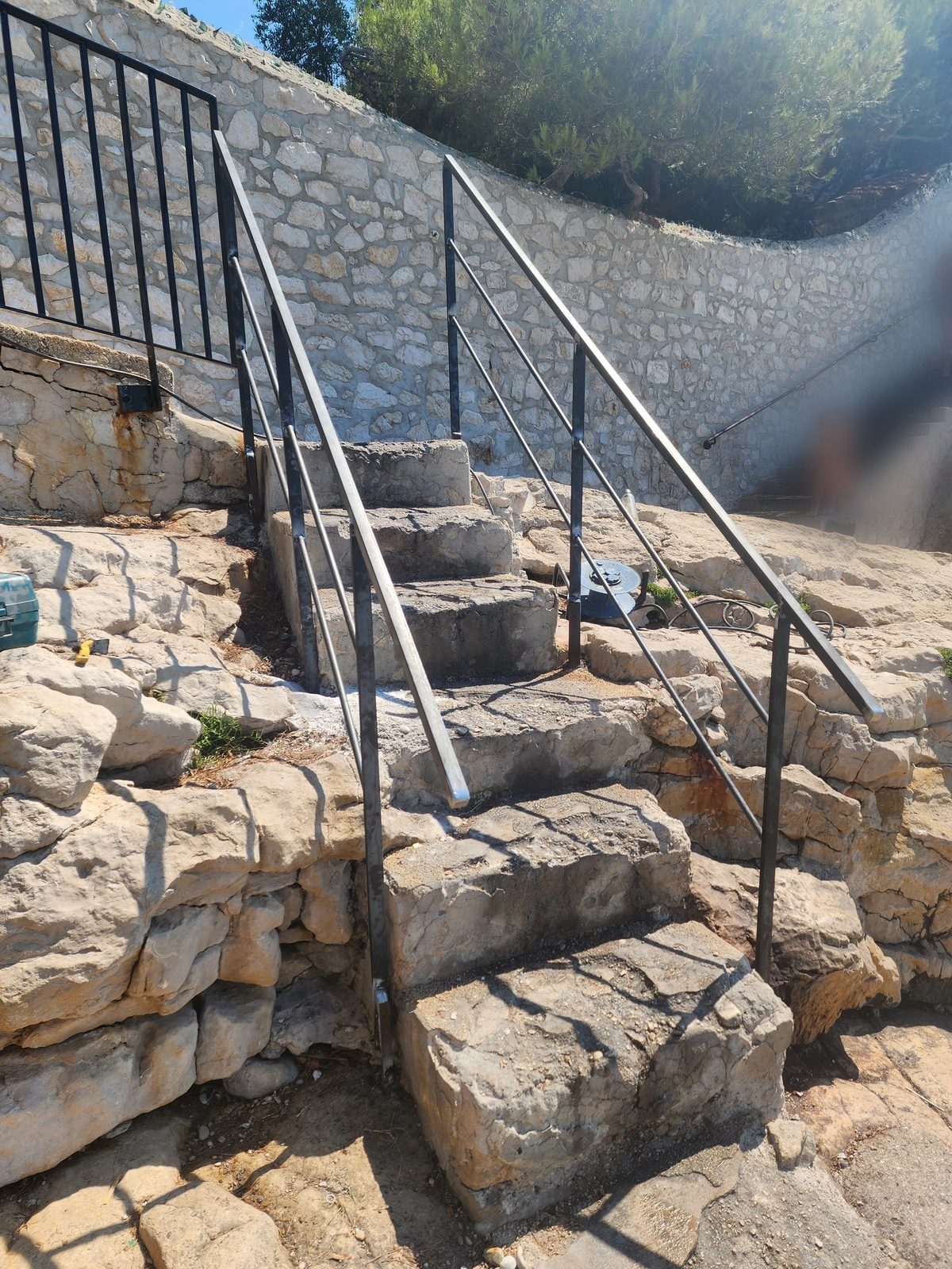 Mains courantes acier en profilés pleins posées sur l'escalier de roche de la plage du Bestouan, à Cassis